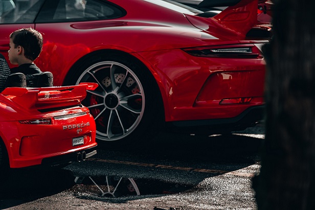 赤いスポーツカーに並び、同じ車種の子供用カーに乗る男の子