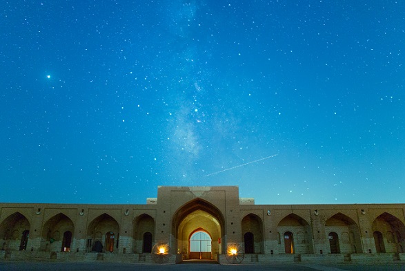 建物の上に広がる星空と、流れ星